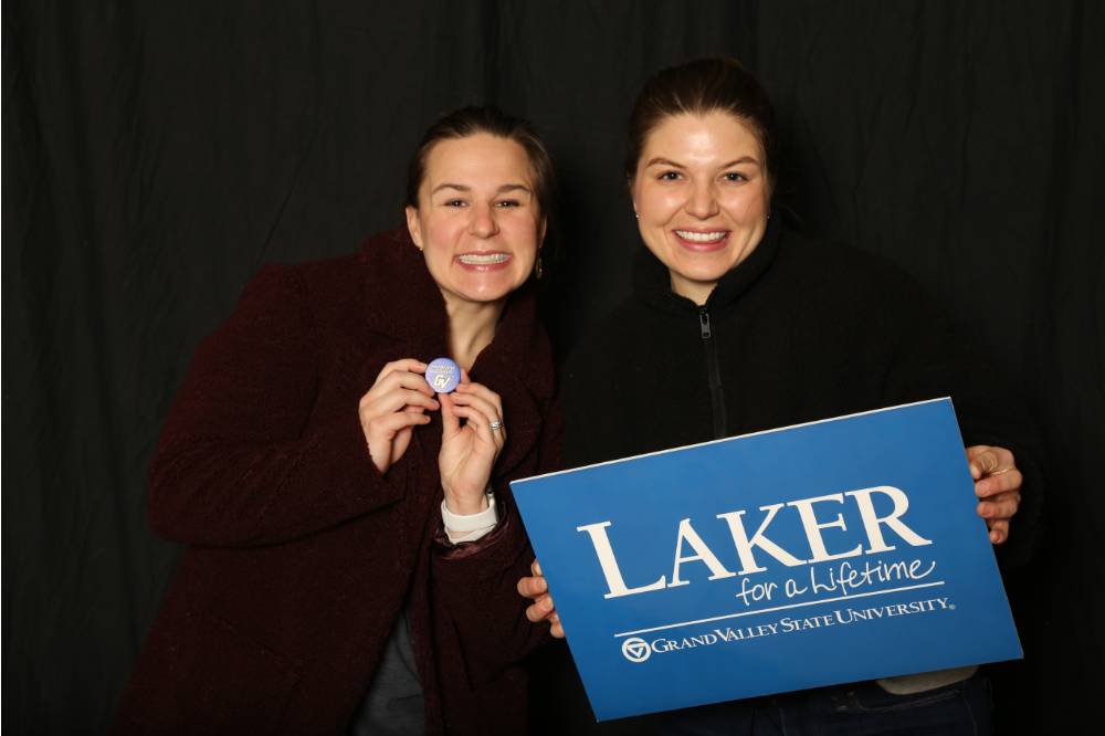 two friends smiling with the laker for a lifetime sign at GradFest